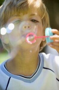 Boy blowing bubbles --- Image by © Royalty-Free/Corbis A child blowing bubbles outdoors on a sunny day.