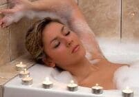 A woman relaxing in a candlelit bath.
